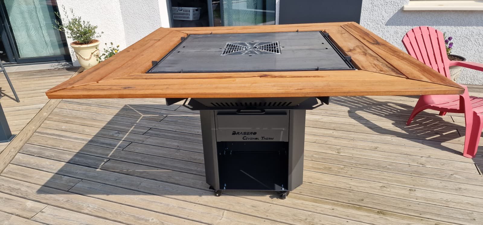 Table brasero anthracite avec entourage en bois sur une terrasse